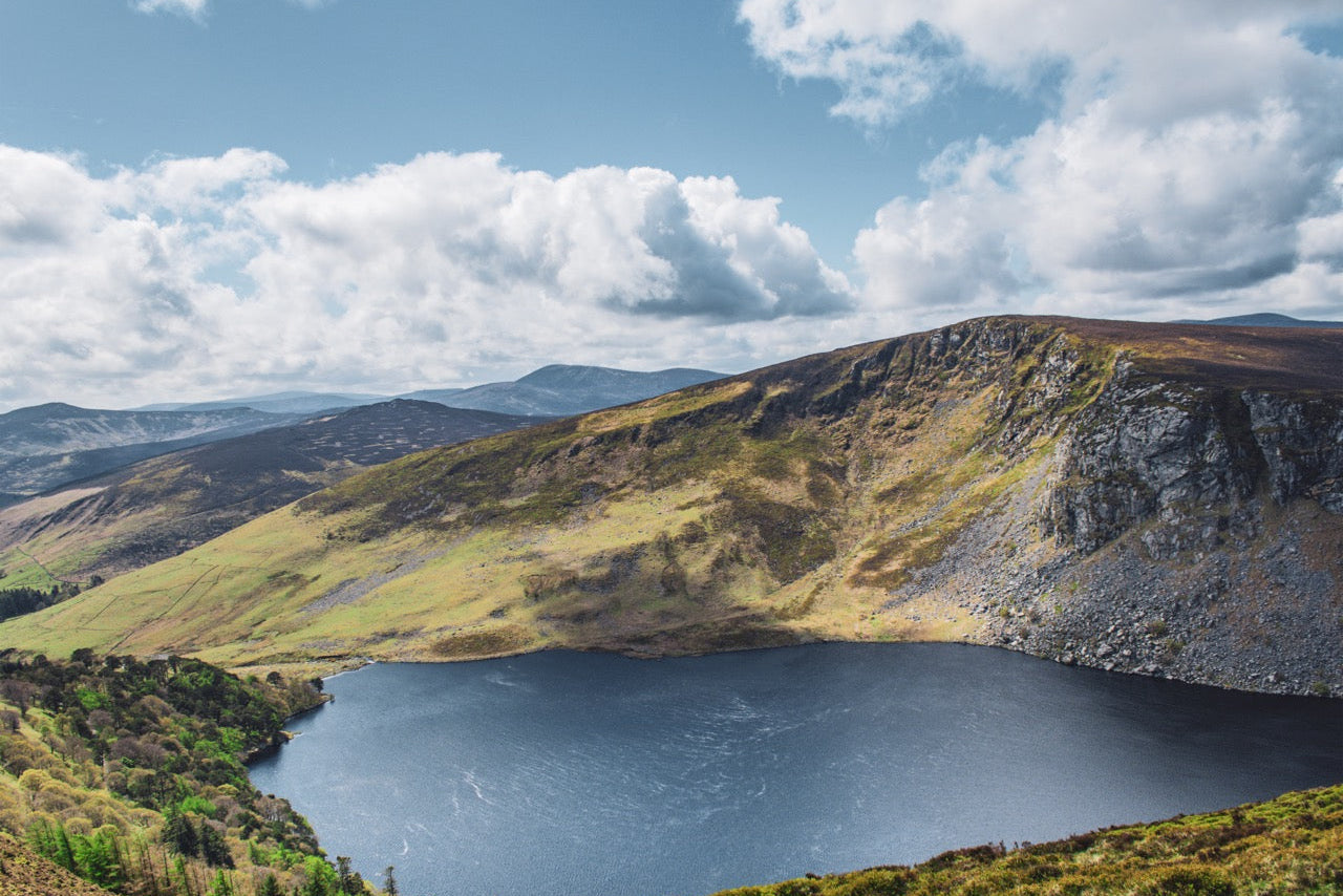 Lake surrounded by mountains under a blue sky with clouds