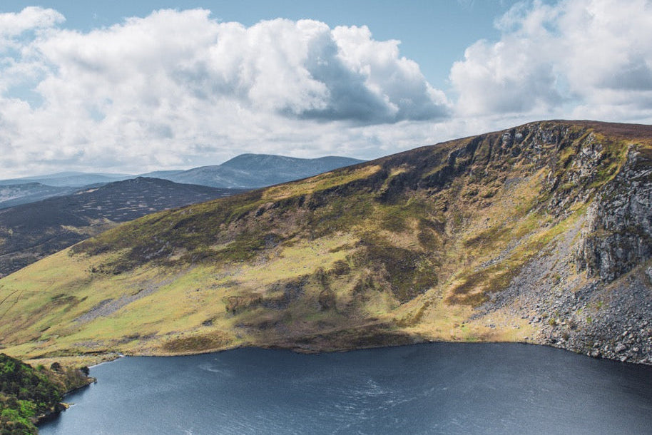 Lake surrounded by mountains under a blue sky with clouds